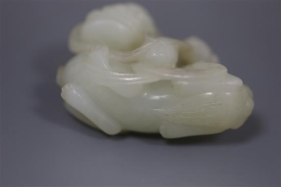 A Chinese pale celadon jade figure of a lion dog and cub, 18th/19th century, L. 6cm, wood stand